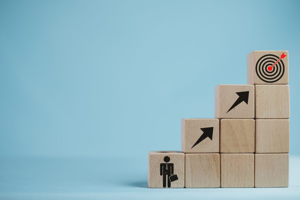 A human figure ascending block steps toward a target, illustrating achieving a career goal.